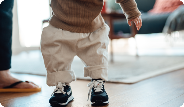 Young child learning to walk in sneakers with adult support, symbolizing a foundation for growth through free cash flow ETF investing, biblical stewardship, and biblically responsible investing.